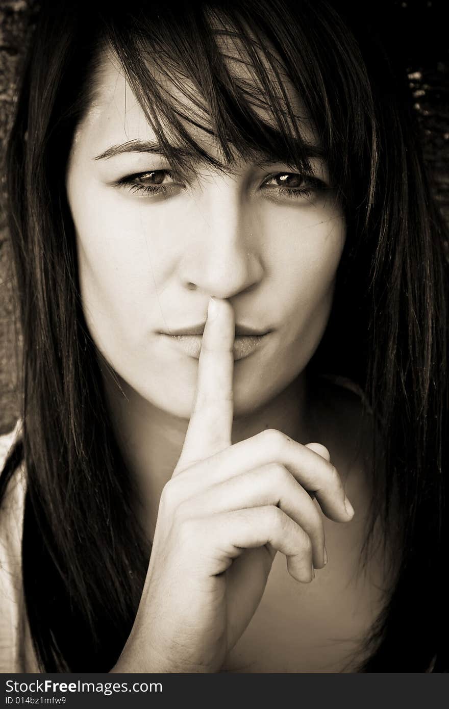 Young woman requesting silence, sepia toned.