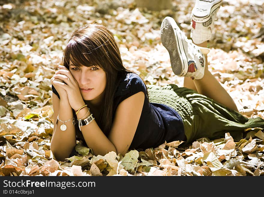 Young woman laying over fallen leaves. Young woman laying over fallen leaves.