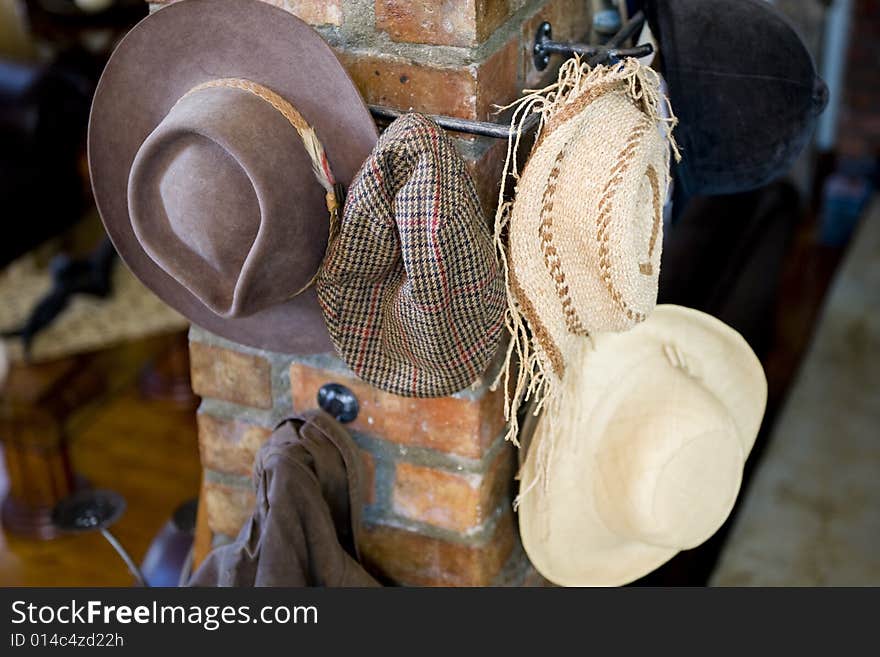 A variety of hats hanging on multiple hooks on a pillar inside the lounge of a modern house.