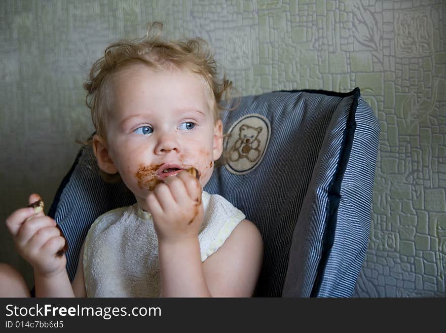 Baby eat chocolate cake on kitchen