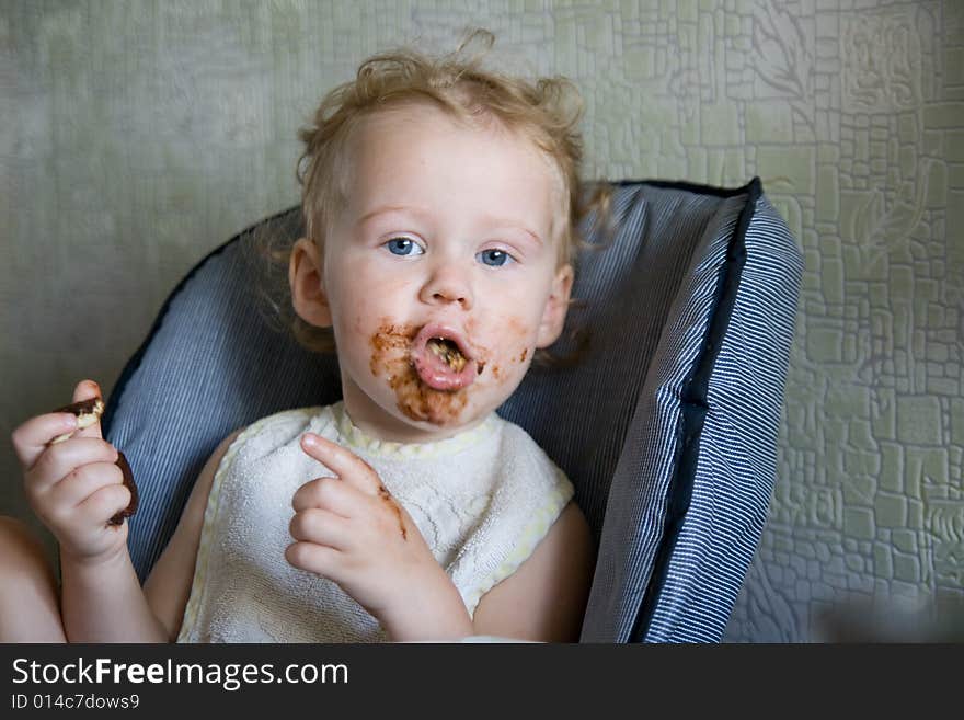 Baby eat chocolate cake on kitchen