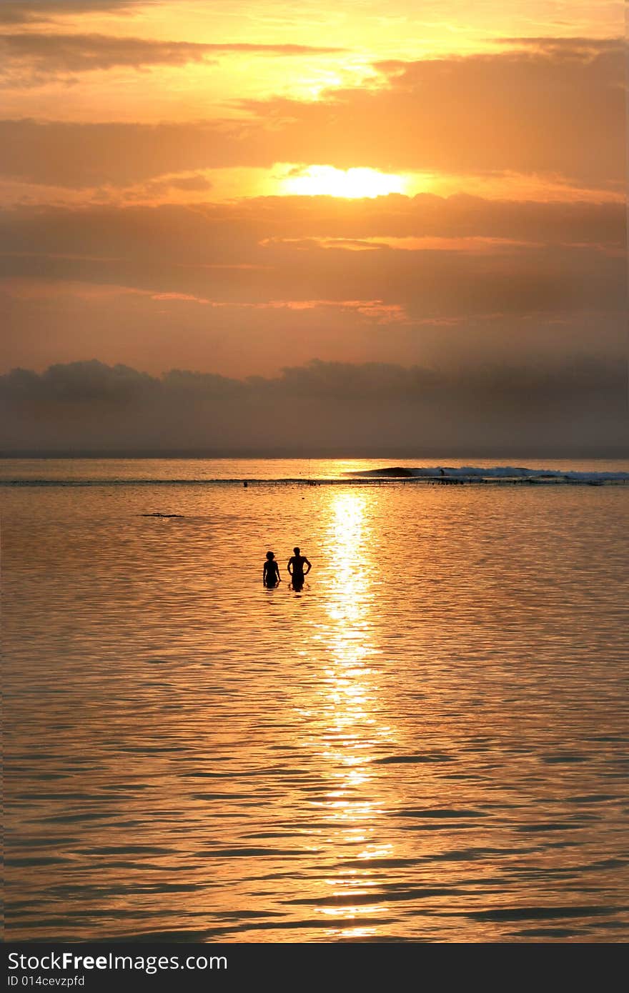 Sunset over lembongen island, bali, indonesia with a couple in the ocean. Sunset over lembongen island, bali, indonesia with a couple in the ocean