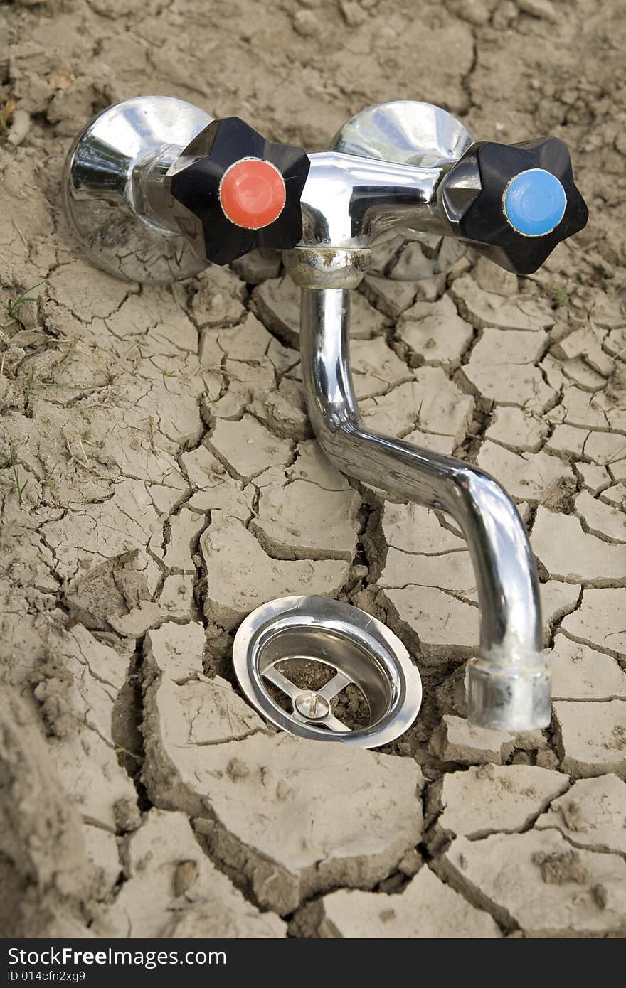 Global Warming Metaphor - dry ground with water outflow and draw-off tap