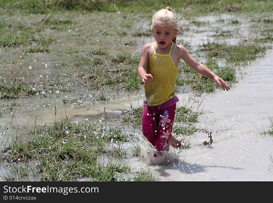 Little girl playing in muddy water dirtying her clothes. Little girl playing in muddy water dirtying her clothes