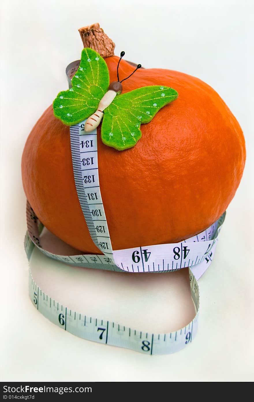 The beautiful green butterfly on a pumpkin and a white measuring tape. A healthy food. Diet. The beautiful green butterfly on a pumpkin and a white measuring tape. A healthy food. Diet