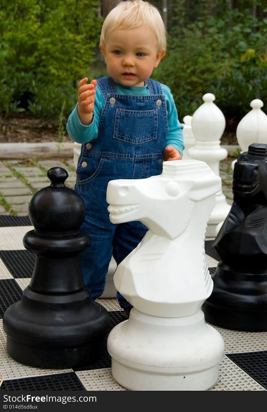 The little boy plays the big chessmen. The little boy plays the big chessmen.