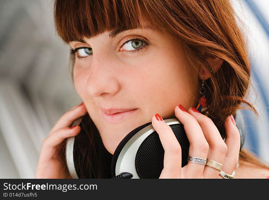 Pretty young girl holding big headphones listening to music. Pretty young girl holding big headphones listening to music