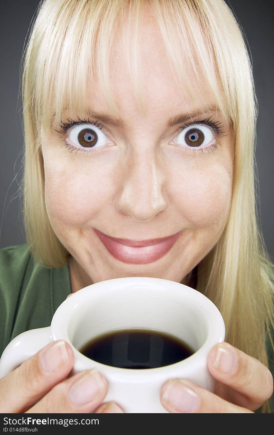 Beautiful Woman Enjoys Her Coffee Against a Grey Background. Beautiful Woman Enjoys Her Coffee Against a Grey Background.