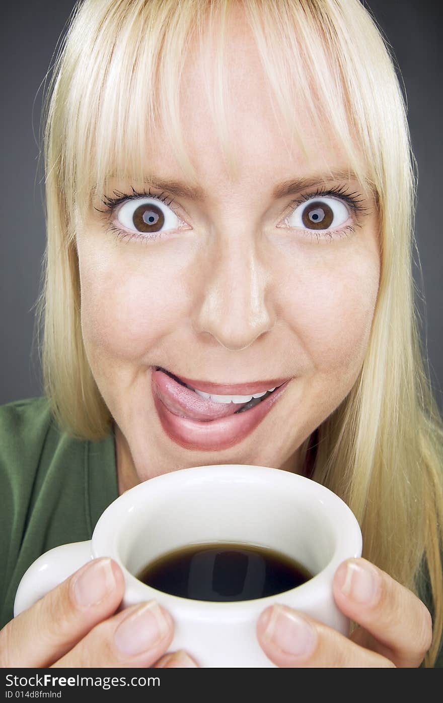 Beautiful Woman Enjoys Her Coffee Against a Grey Background. Beautiful Woman Enjoys Her Coffee Against a Grey Background.