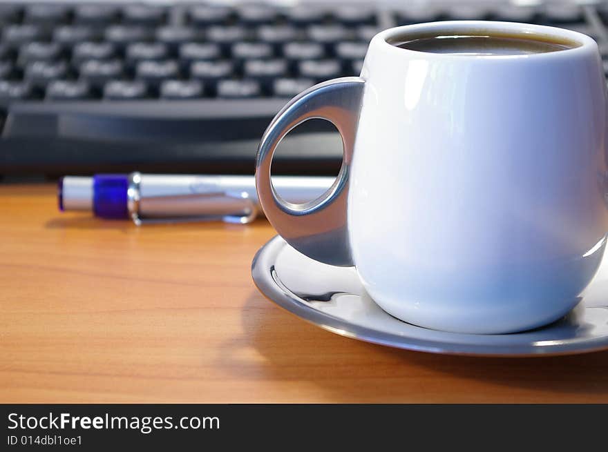 Cup of coffee, keyboard and blue pen on a table. Cup of coffee, keyboard and blue pen on a table