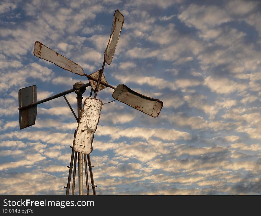 Rusted windmill with cumulus puffy clouds on the background. Rusted windmill with cumulus puffy clouds on the background