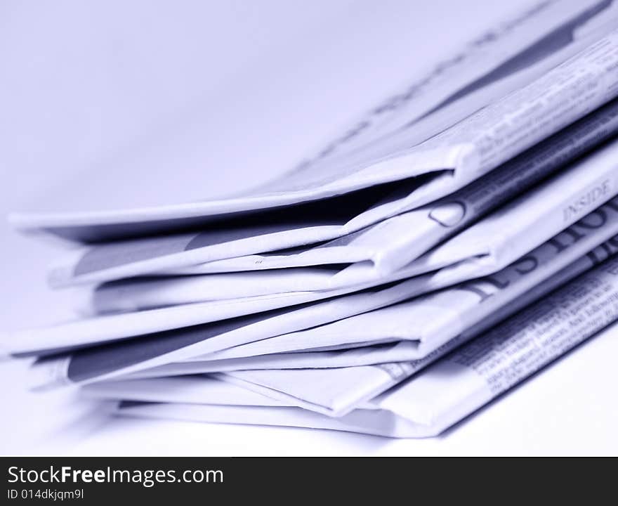 Blue tinted newspapers on light background shot with very shallow depth of focus. Blue tinted newspapers on light background shot with very shallow depth of focus