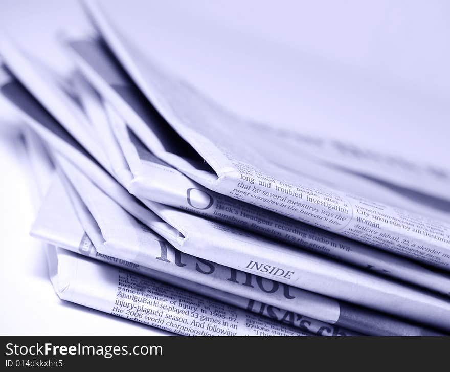 Blue tinted newspapers on light background shot with very shallow depth of focus. Blue tinted newspapers on light background shot with very shallow depth of focus