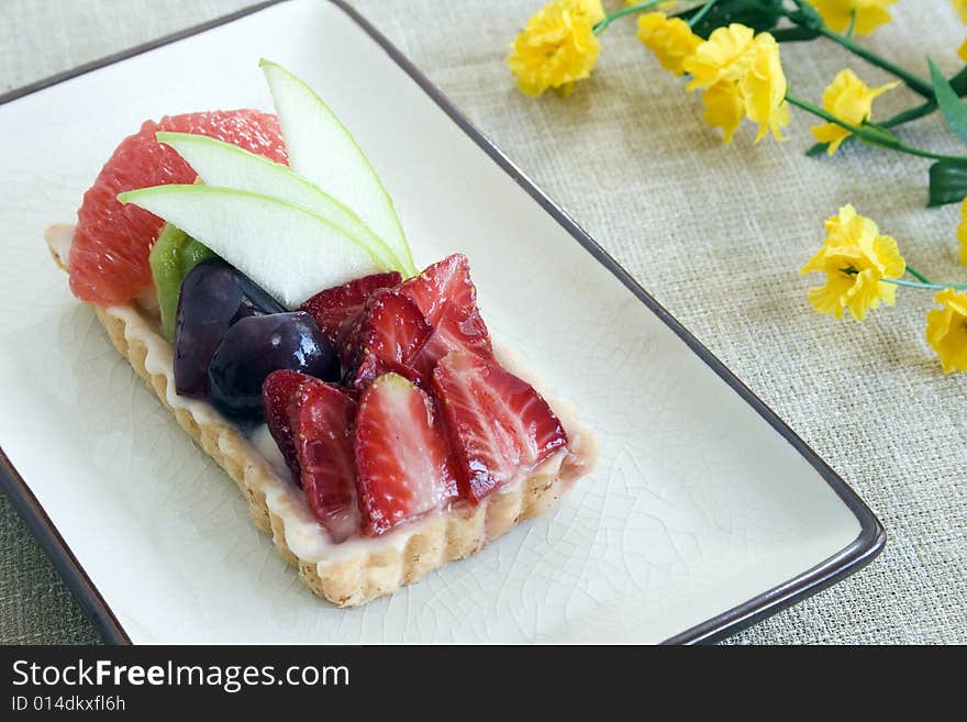 Close up of a fruit cake with strawberry, green apple, grapes, kiwi and grapefruit. Focus on the middle part.