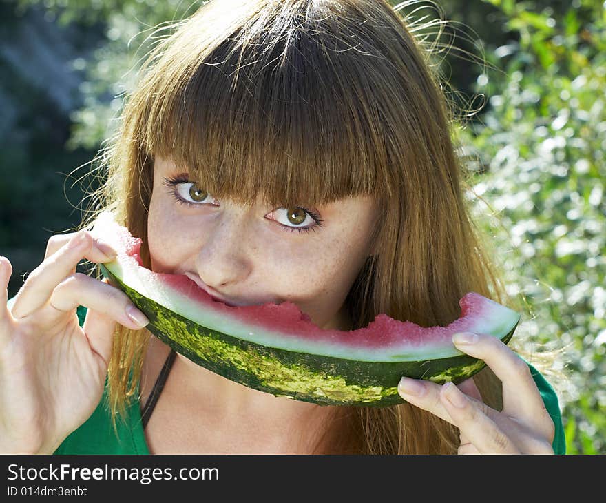 Pretty girl in green dress eating watermelon. Pretty girl in green dress eating watermelon