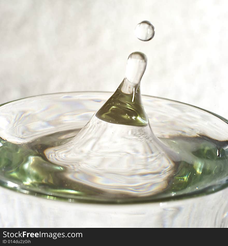 Droplet of water splashing from glass of water with reflections and highlights. Droplet of water splashing from glass of water with reflections and highlights