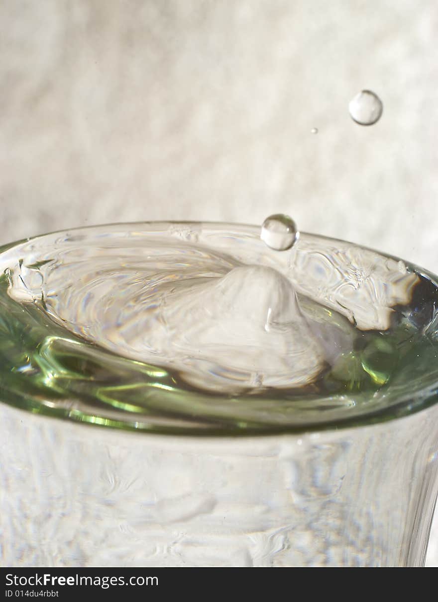 Droplets of water splashing from glass of water with reflections and highlights. Droplets of water splashing from glass of water with reflections and highlights