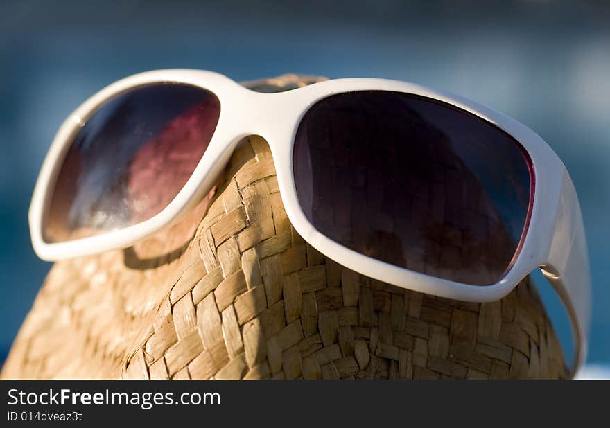 A Straw Hat With Sun Glasses Sitting Beside Pool