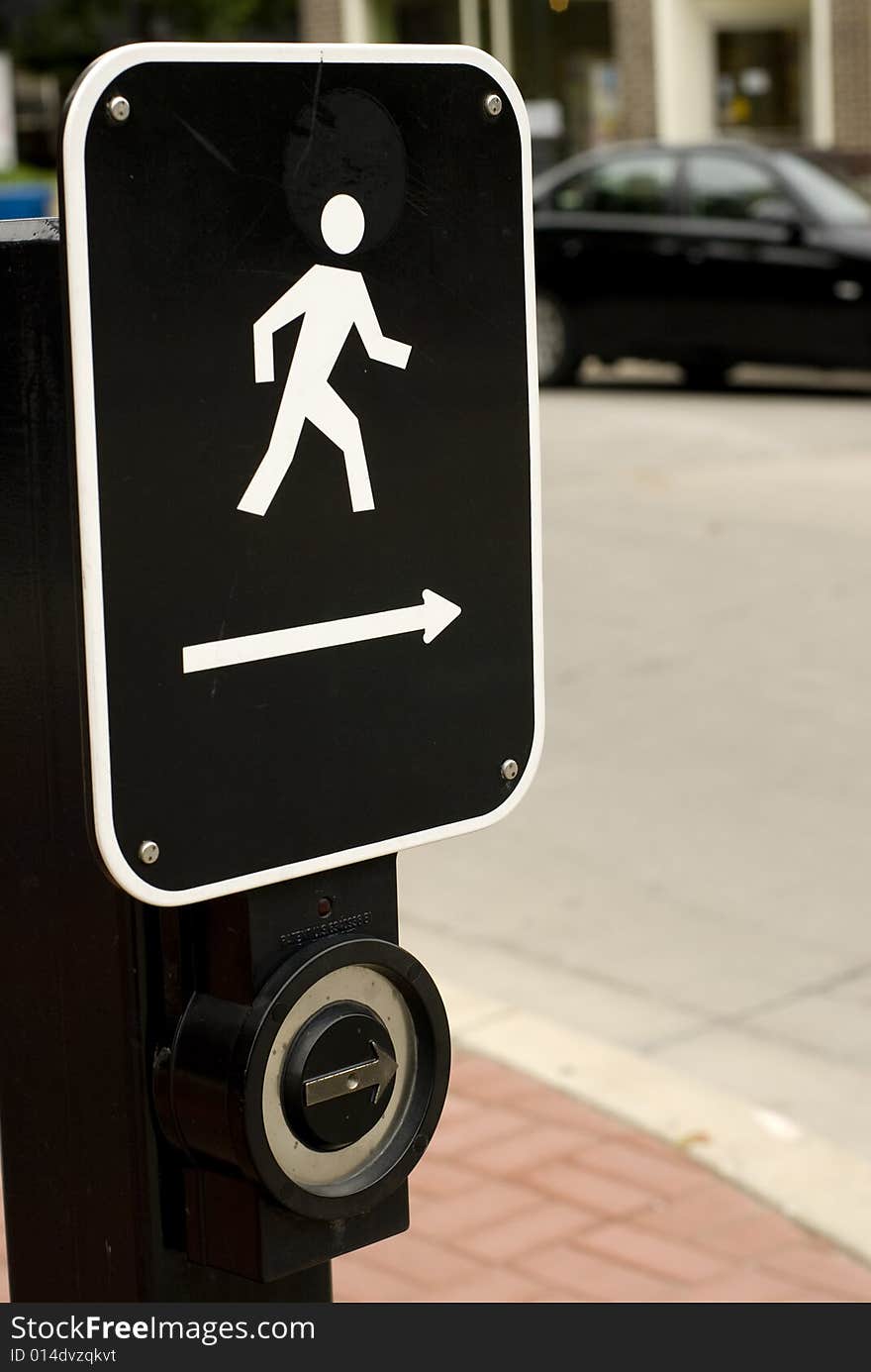 Black & white metal street crossing sign affixed to a light post