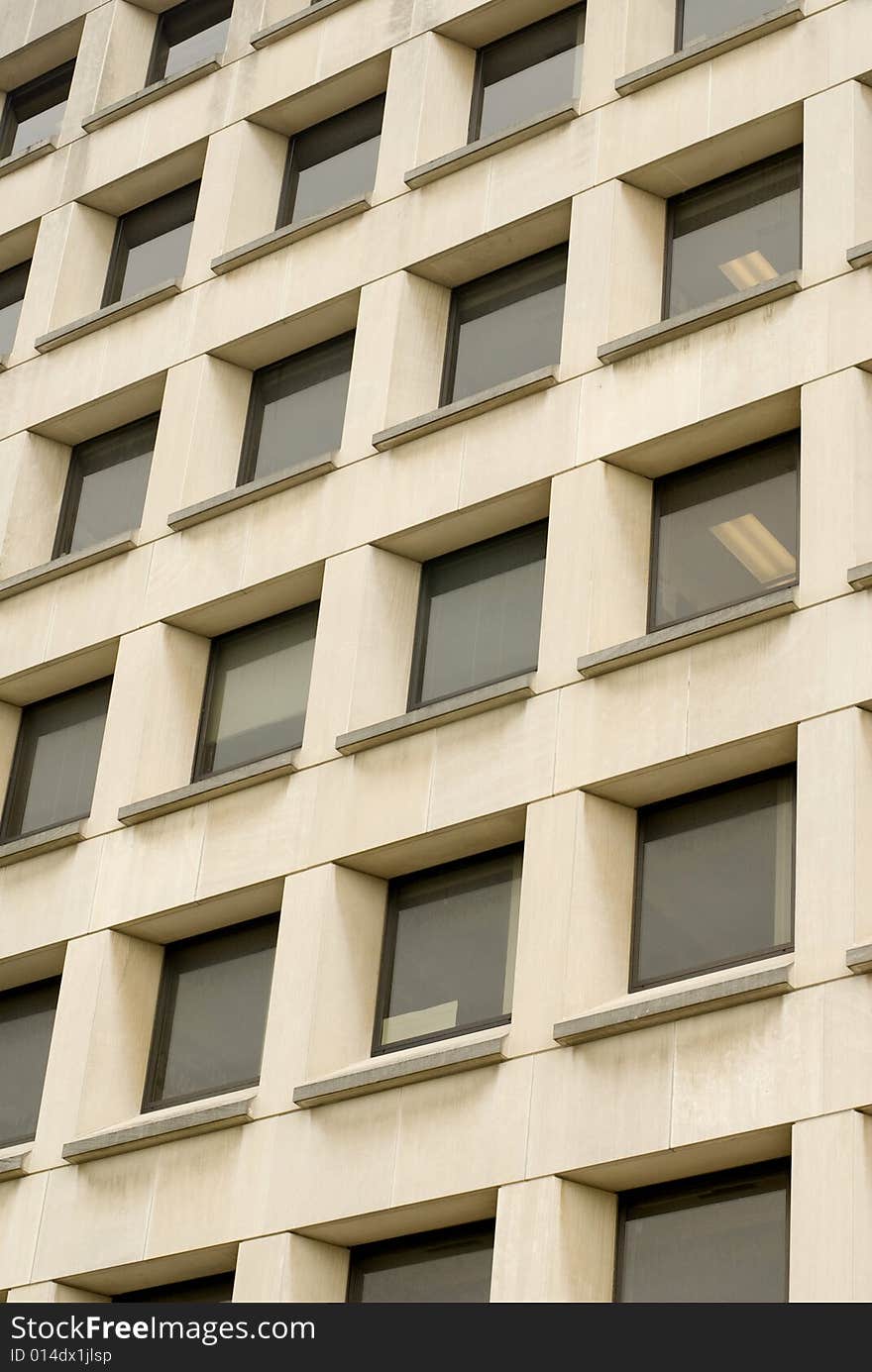 Close shot of a cream-colored building with black windows. Close shot of a cream-colored building with black windows