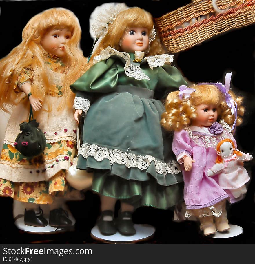 Still of collectible porcelain doll display with bounce and fill and background replaced; and their little basket hanging by them; one holding her own babydoll, one holding purse; a very small part of my wifes extensive collection. one wears green outfit; one dressed in purple doll clothes and one in a white print. Something that might interest doll collectors and doll magazines.