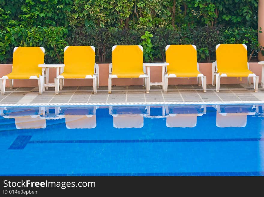 Yellow loungers reflecting in a swimming pool. Yellow loungers reflecting in a swimming pool.