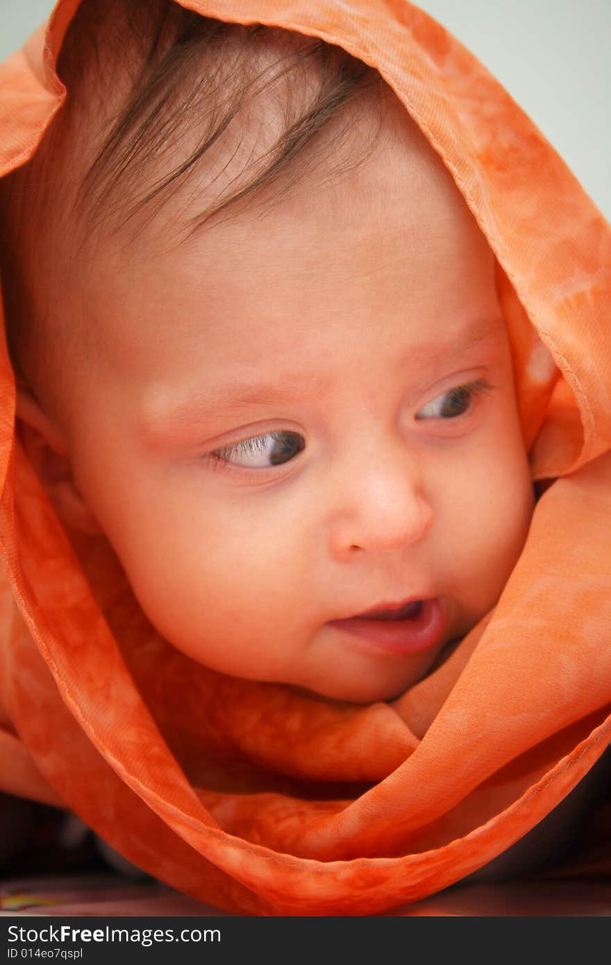 Little baby wrapped in orange shawl