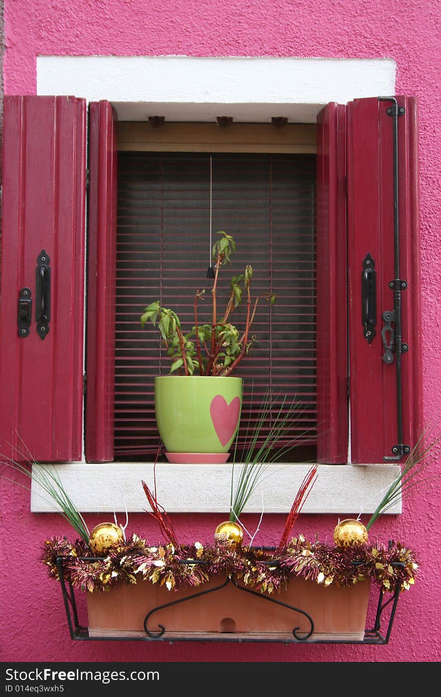 A flower pot with pink heart in window on pink wall. A flower pot with pink heart in window on pink wall