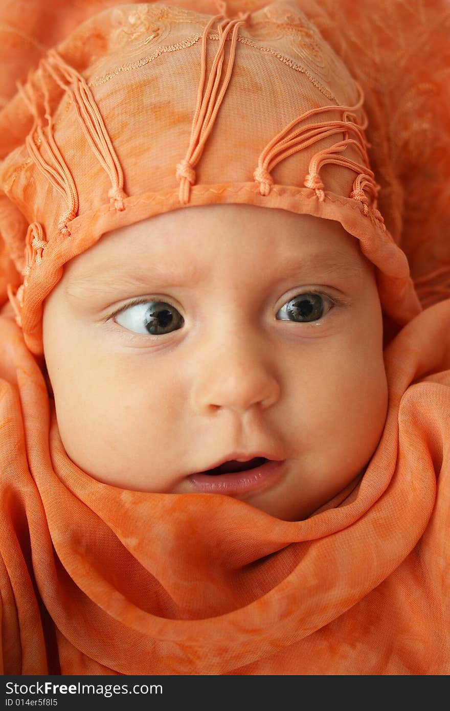 Little baby wrapped in orange shawl