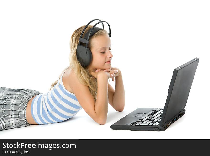 Teen girl on laptop with earphones isolated on white