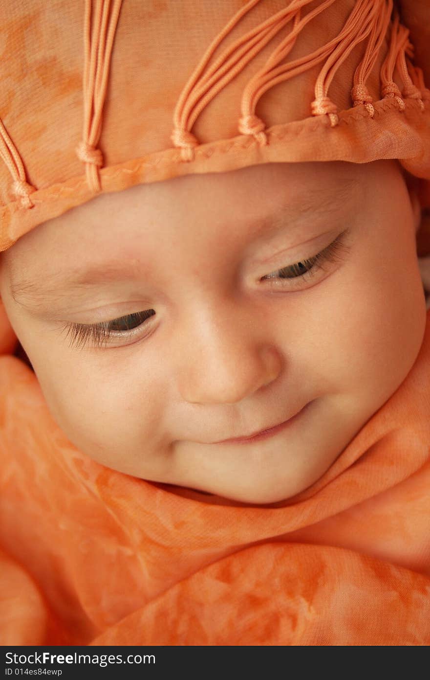 Little baby wrapped in orange shawl