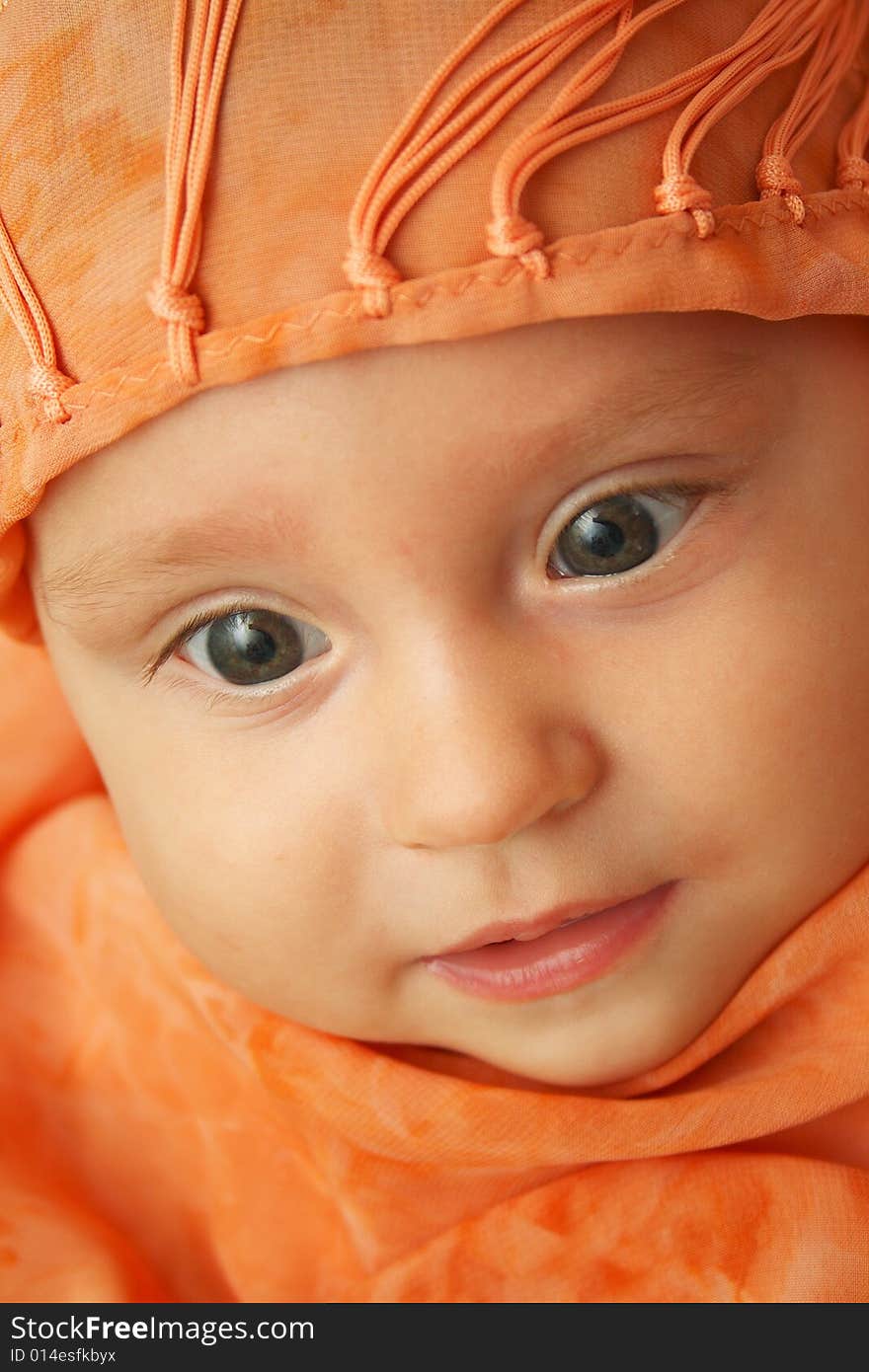 Little baby wrapped in orange shawl