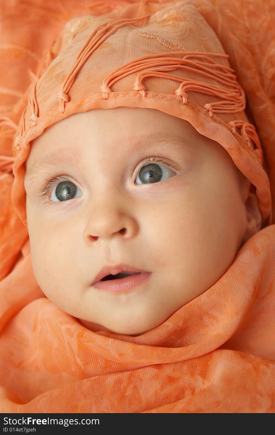 Little baby wrapped in orange shawl