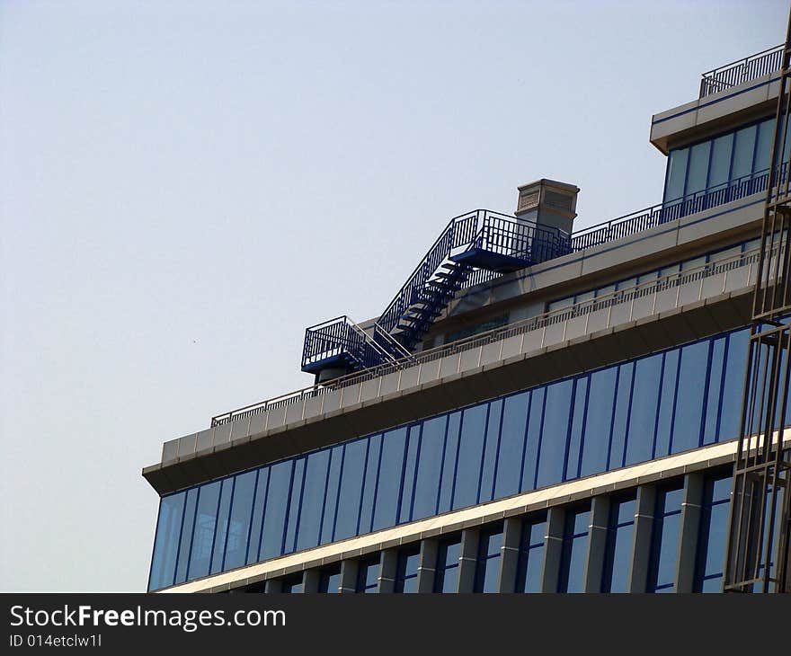 Part of building. Glass facade. Pipe and stair on a roof. Part of building. Glass facade. Pipe and stair on a roof.