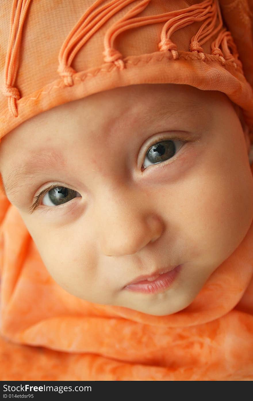 Little baby wrapped in orange shawl