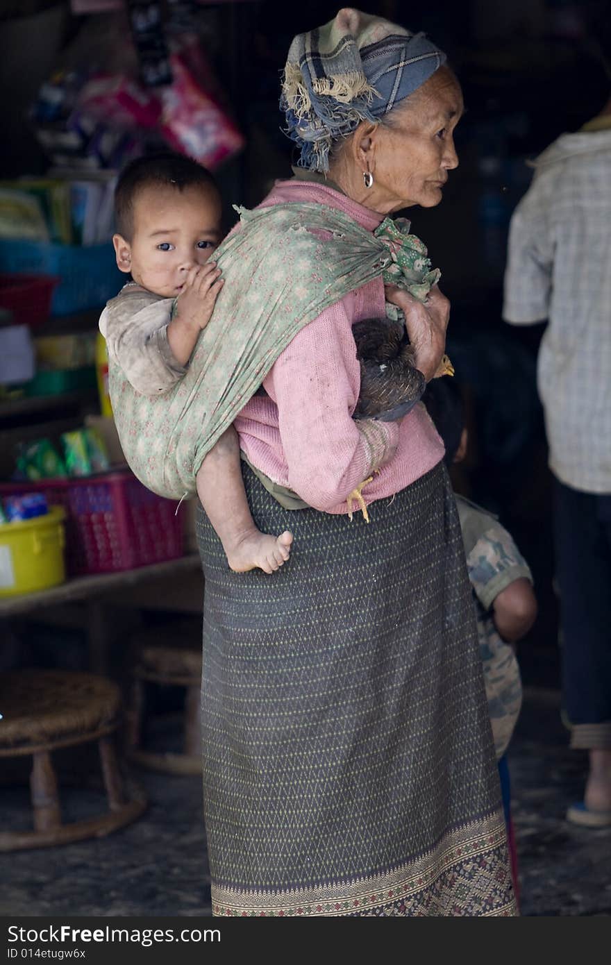 Asia, old woman with grandchild and chicken in a village of Laos