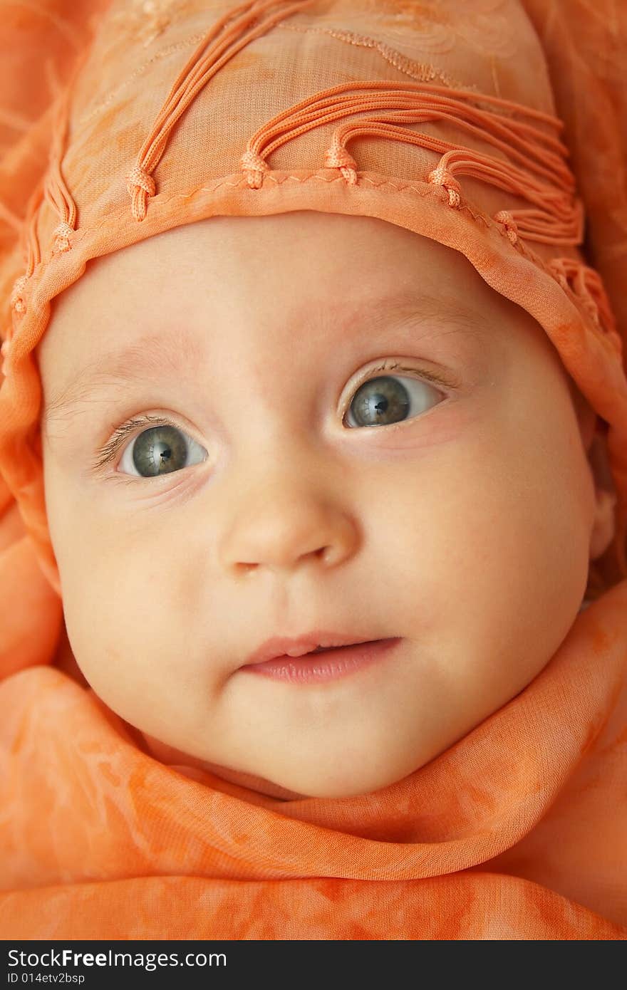 Little baby wrapped in orange shawl