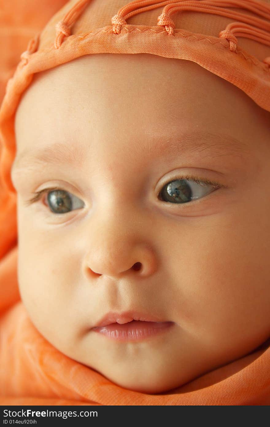 Little baby wrapped in orange shawl