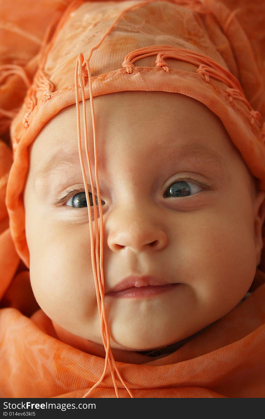 Little baby wrapped in orange shawl