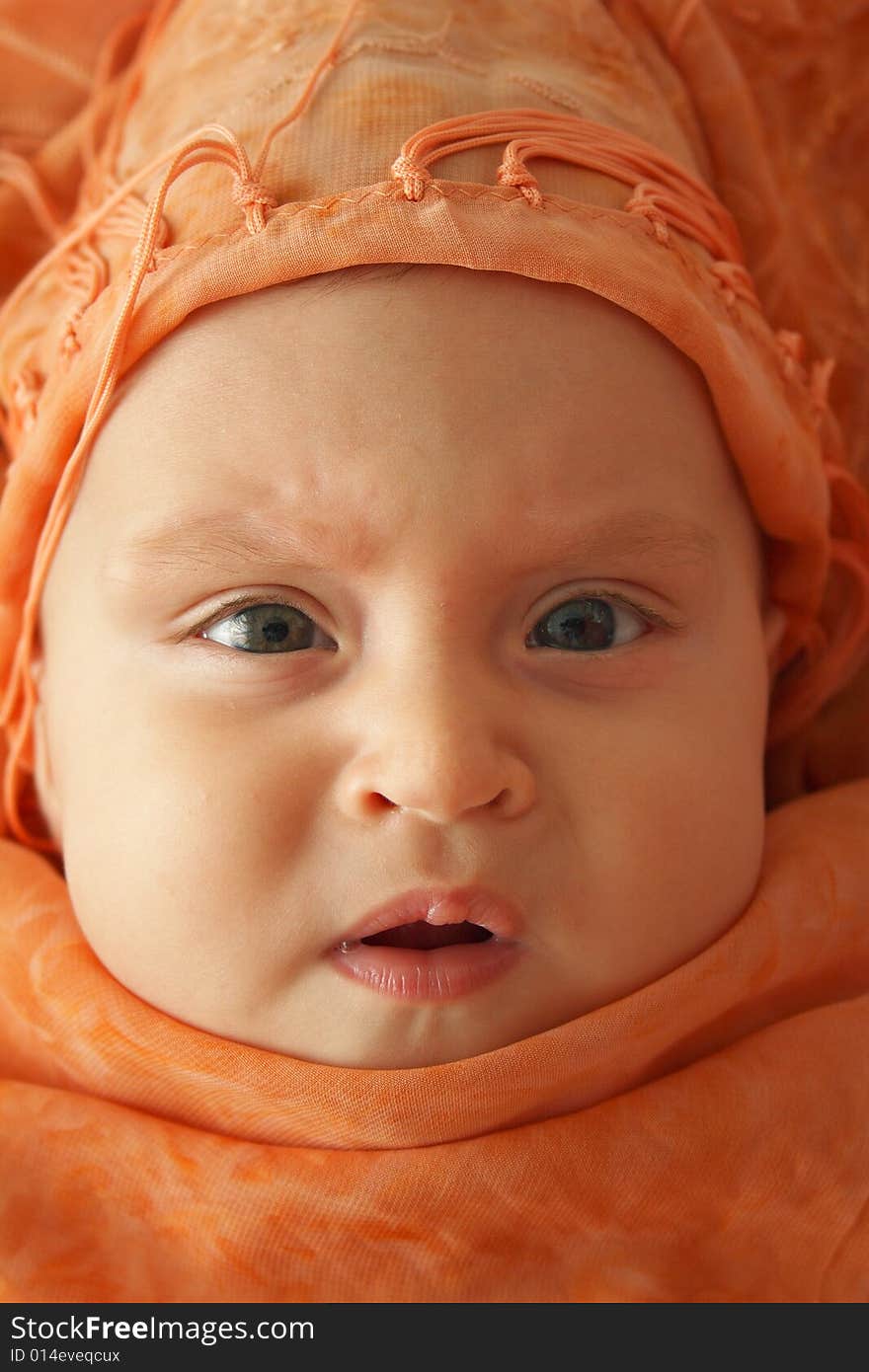 Little baby wrapped in orange shawl