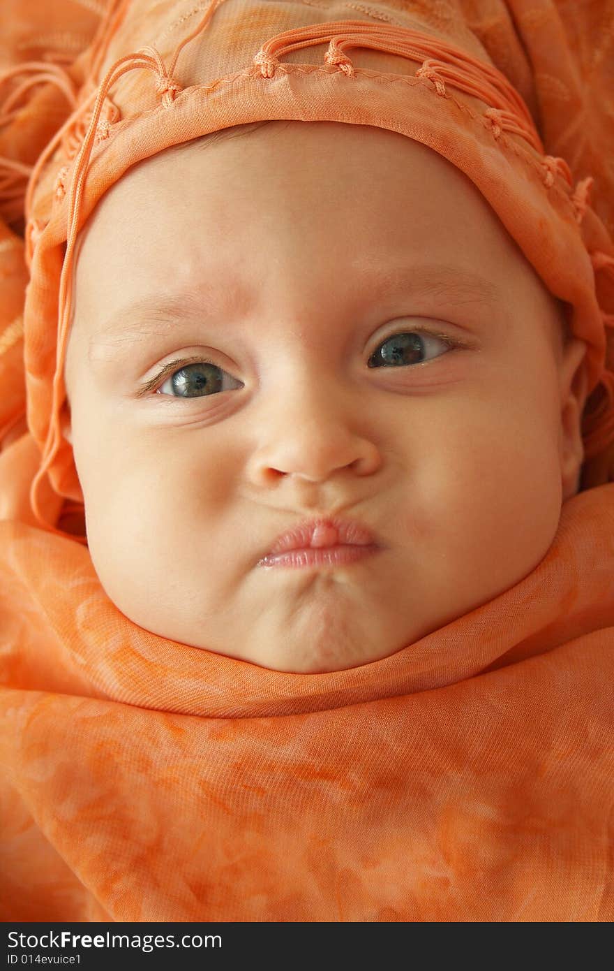 Little baby wrapped in orange shawl