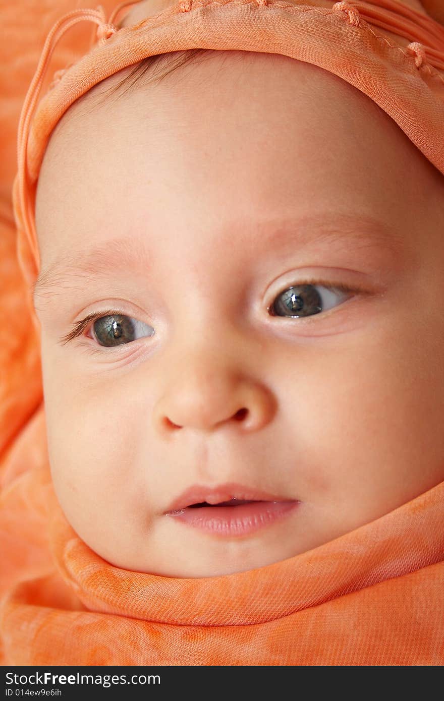 Little baby wrapped in orange shawl