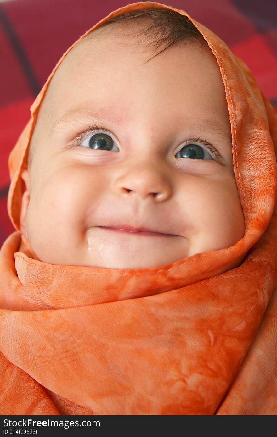 Little baby wrapped in orange shawl