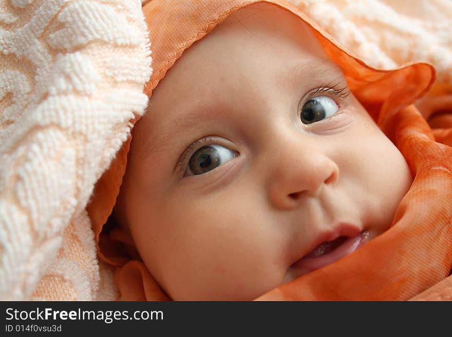 Little baby wrapped in orange shawl