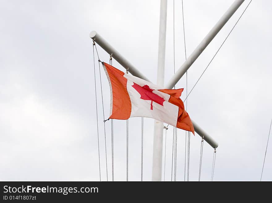 A ships mast flying a Canadian flag. A ships mast flying a Canadian flag