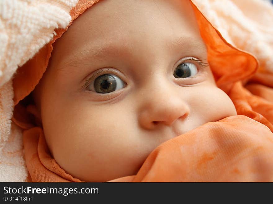 Little baby wrapped in orange shawl