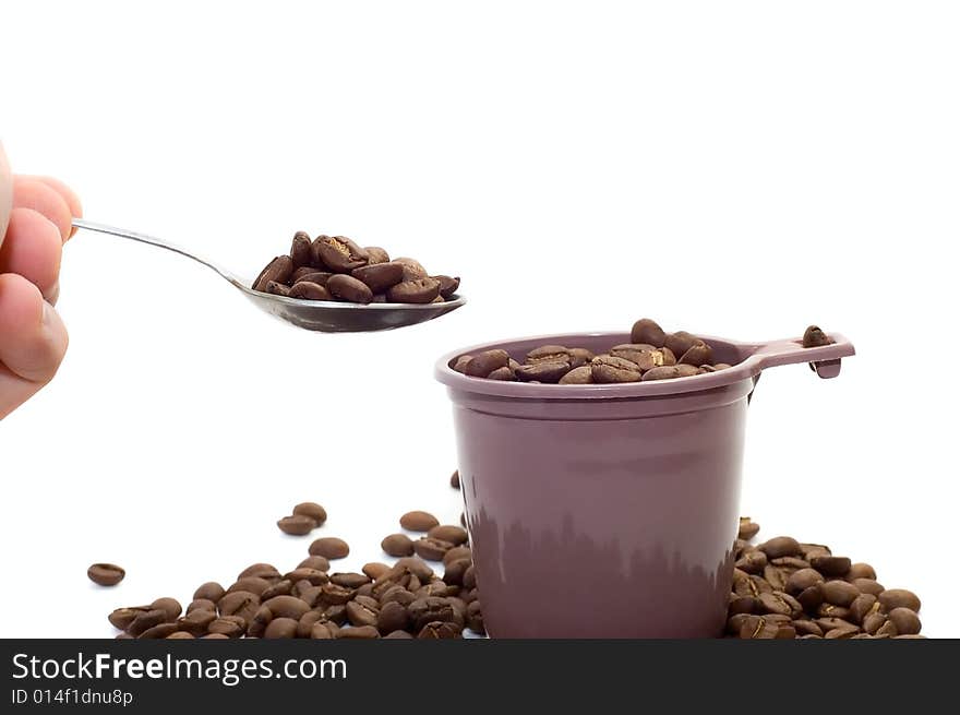 Hand with spoon. Cup with coffee beans on white