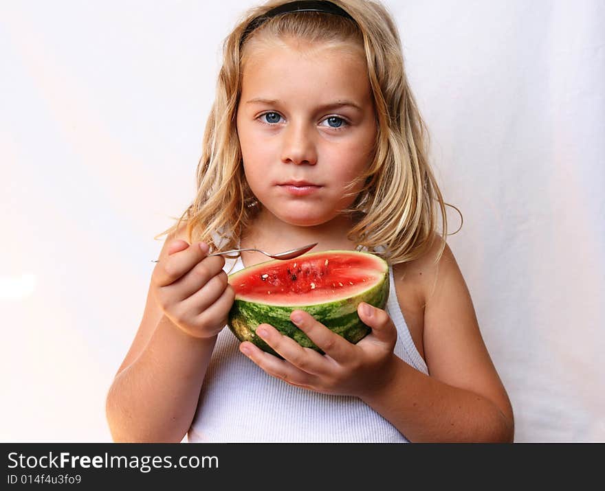 The boy with blond hair is eating melon. The boy with blond hair is eating melon.