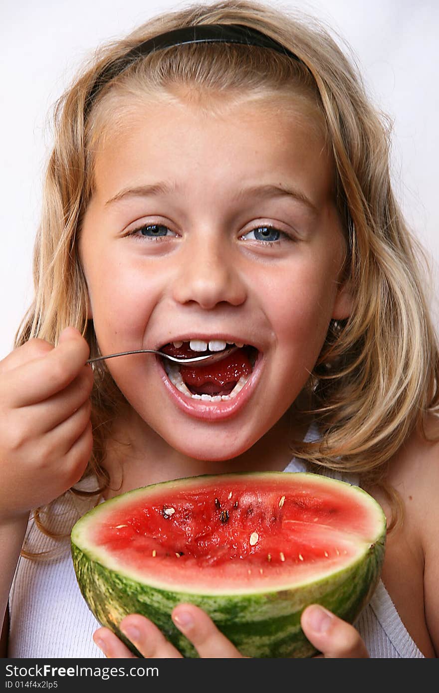 The boy with blond hair is eating melon. The boy with blond hair is eating melon.