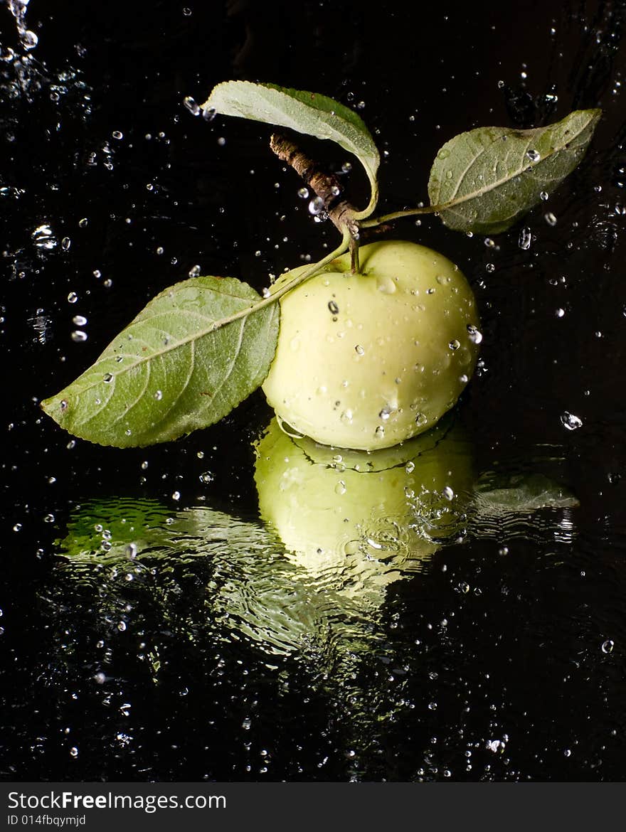 Fresh apple with water splashes on a mirror surface. Fresh apple with water splashes on a mirror surface